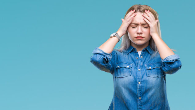 Young blonde woman over isolated background suffering from headache desperate and stressed because pain and migraine. Hands on head.
